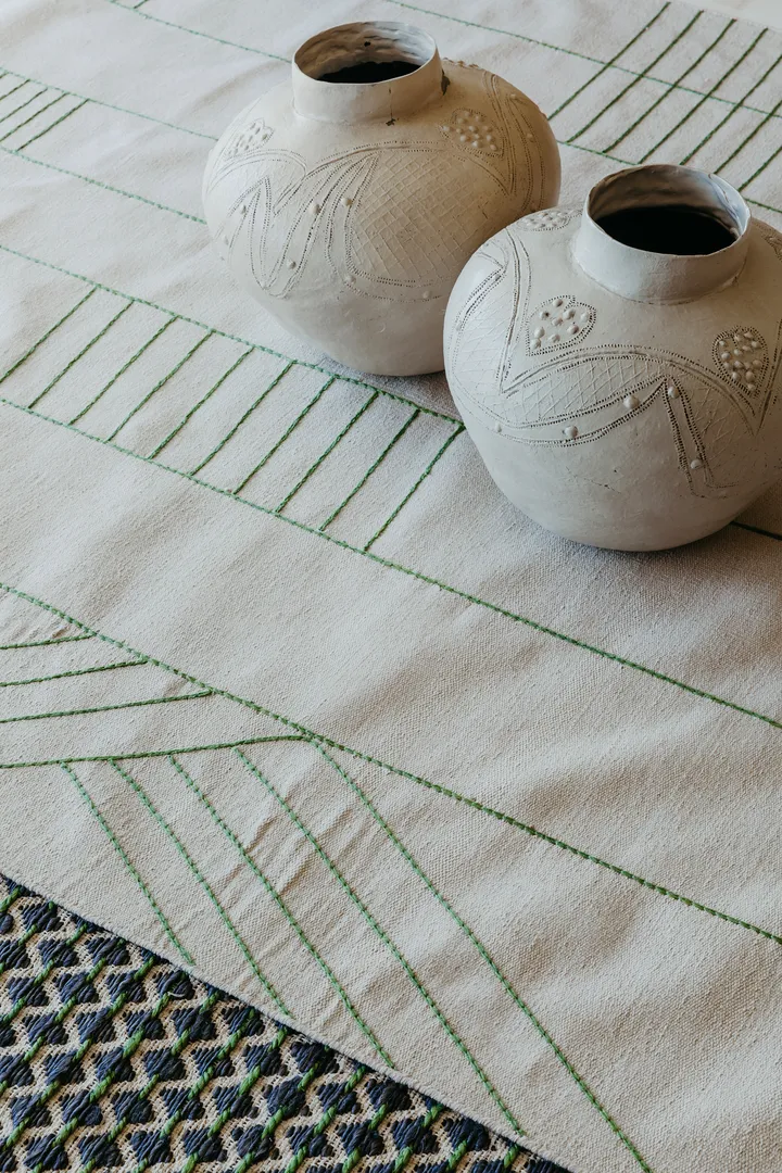 Woven Bliss – Birch Green Rug with thin green lines and pots on it