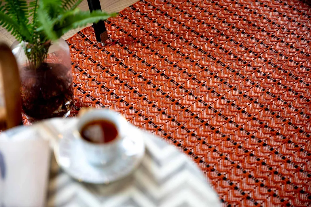 Woven Bliss – a cup of tea on a table sitting atop Dune Orange Rug