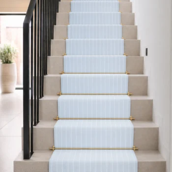 Woven Bliss – Powder blue Kensington Fine Line stair runner installed on cream staircase with brass stair rods