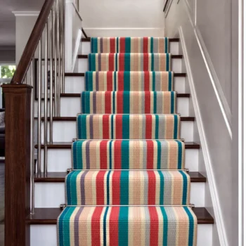 Woven Bliss – Colourful Meridian Stripe Merino stair runner installed on a traditional staircase with wooden treads and decorative stair rods