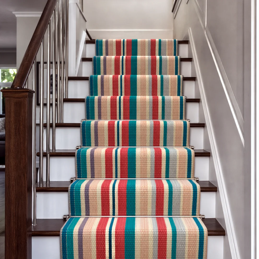 Woven Bliss – Colourful Meridian Stripe Merino stair runner installed on a traditional staircase with wooden treads and decorative stair rods