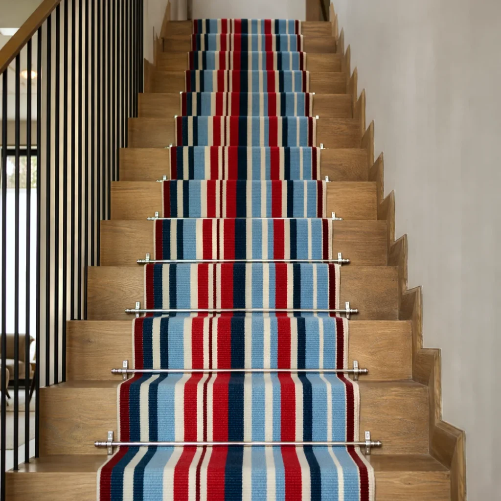 Meridian Stripe Merino stair runner in red, blue and cream installed on a wooden staircase with stainless steel stair rods