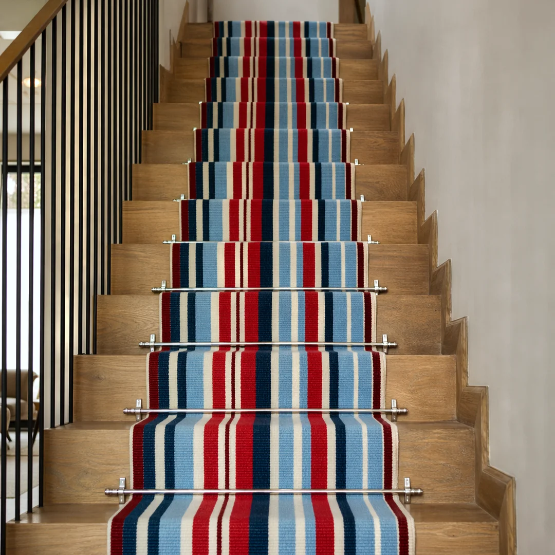 Woven Bliss – Meridian Stripe Merino stair runner in red, blue and cream installed on a wooden staircase with stainless steel stair rods